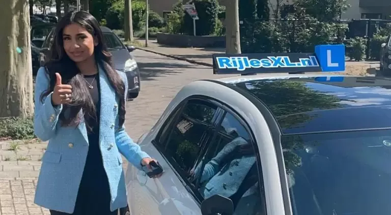 Leerling geeft duim omhoog bij de lesauto van RijlesXL